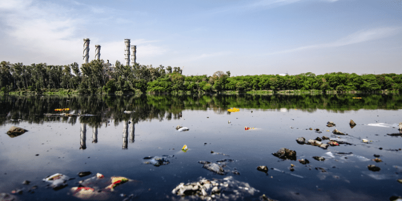 Plastic and pollution Plastic pollution floating in a lake with power plant towers in the background -Nat